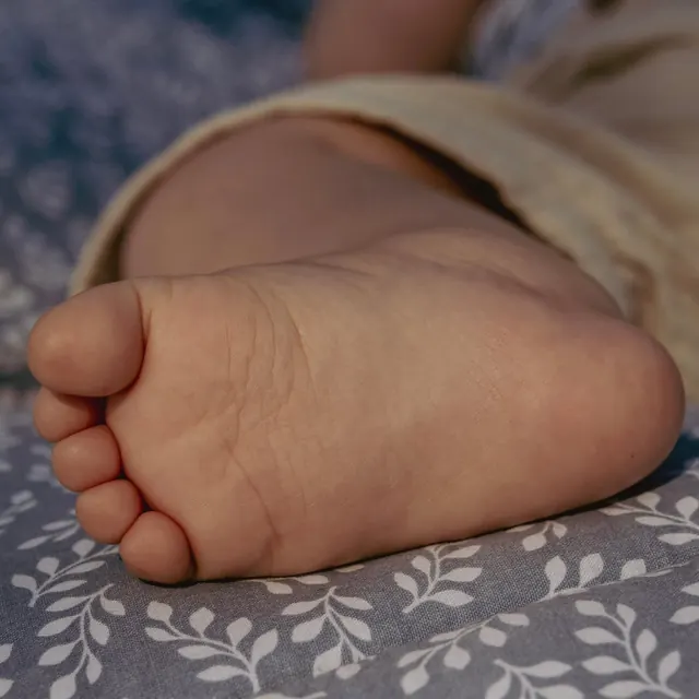 Kleiner Babyfuß auf einer geblümten Decke